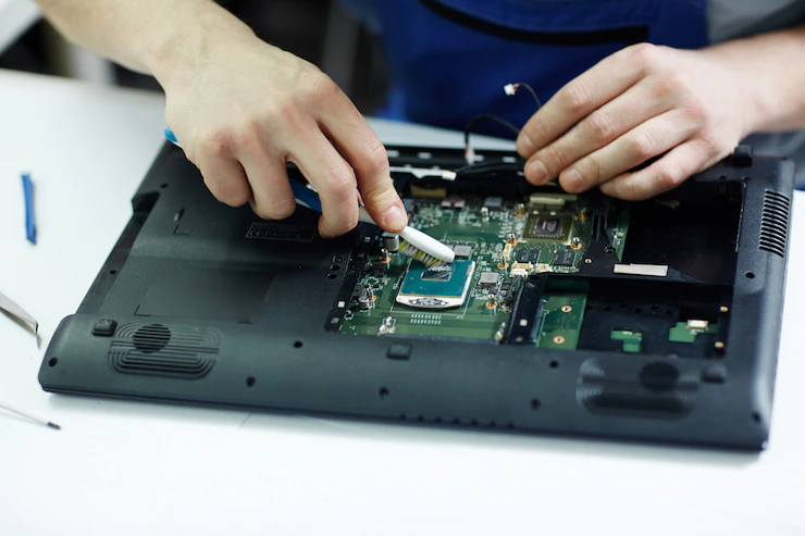 technician-clearing-circuit-board-disassembled-laptop